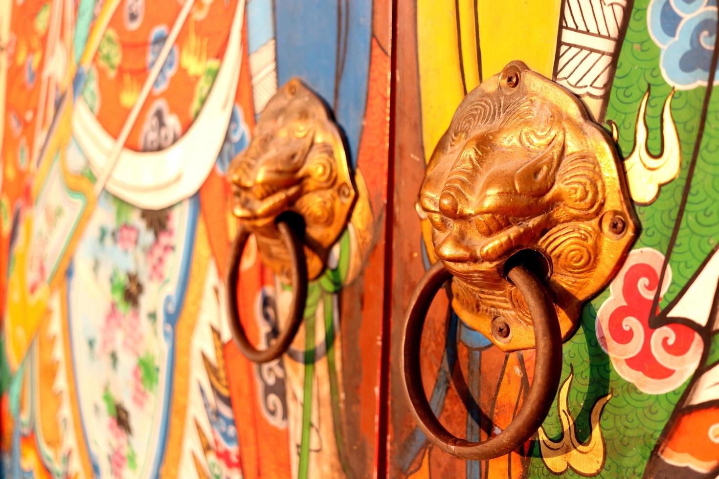 Brass door knobs are on bright colorful door and shape tiger head, the door knobs are design chinese style in shrine, Thailand. photo
