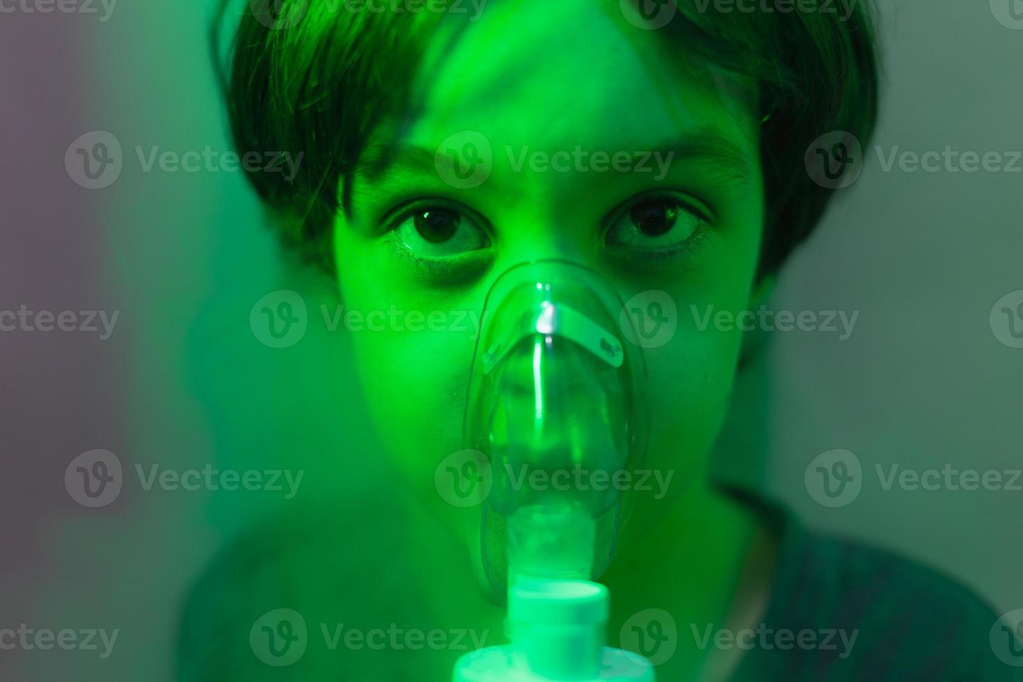 the child does inhalation, the boy inhales the medicine through the mask photo