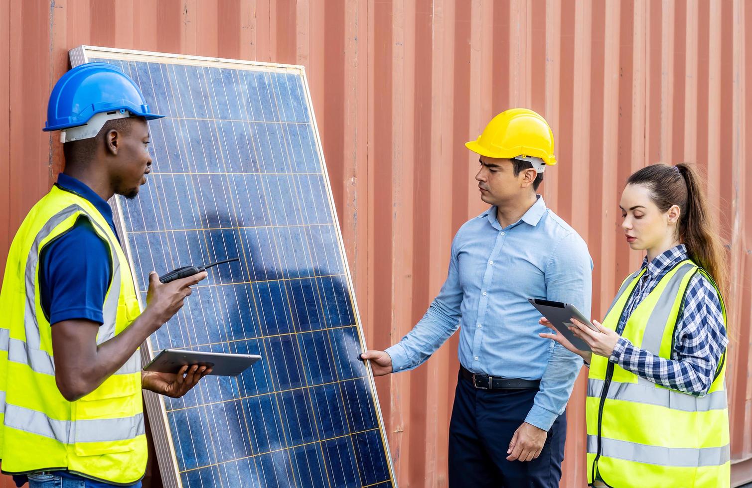 dos ingenieros de energía masculinos con su colega mujer discutiendo un nuevo proyecto a punto de invertir en la instalación de células solares fuera del edificio o fábrica industrial foto