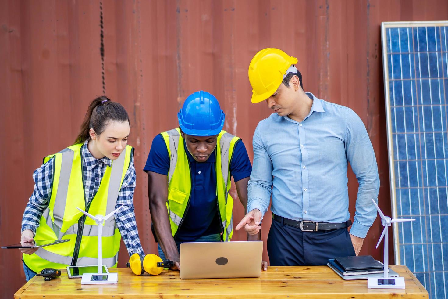 dos ingenieros de energía masculinos con su colega mujer discutiendo un nuevo proyecto a punto de invertir en la instalación de células solares fuera del edificio o fábrica industrial foto