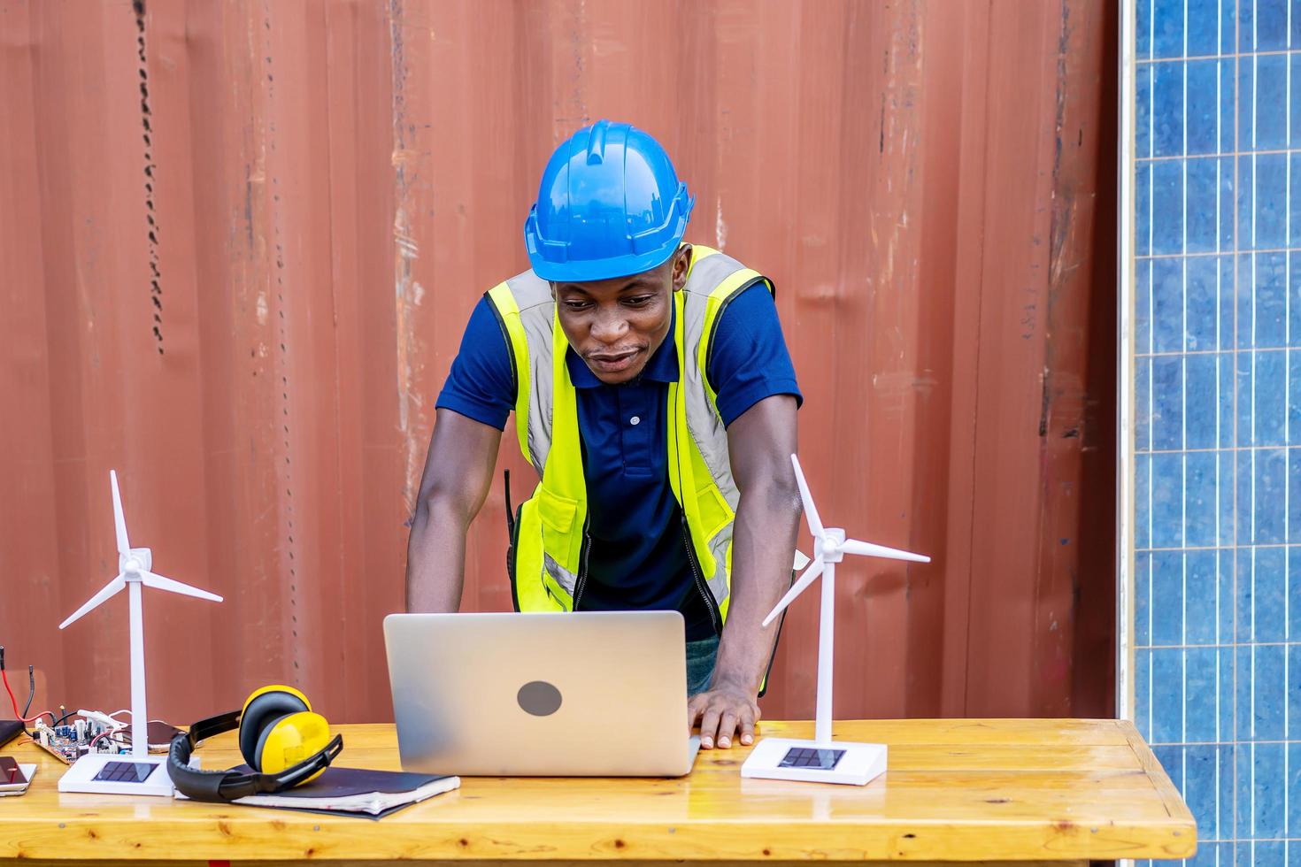 Ecology engineer typing on laptop and working on project. On desk are windmill models. Sustainable development concept photo