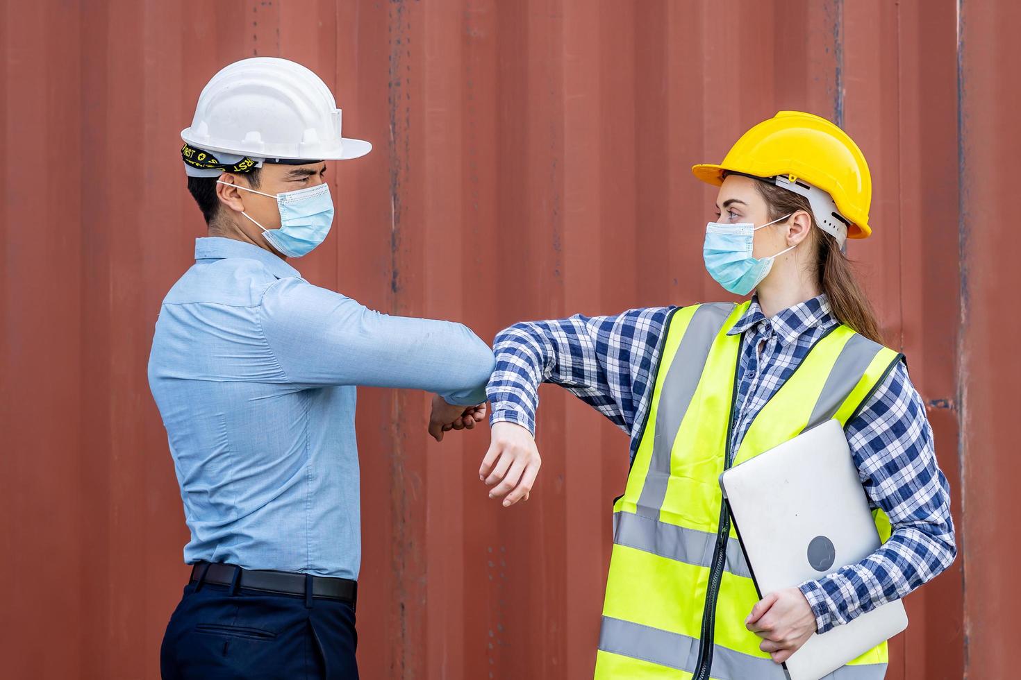 Two Engineer man and woman with medical mask bumping elbows to hello say hi no touching protect coronavirus covid 19, keep new normal social distancing during coronavirus pandemic photo