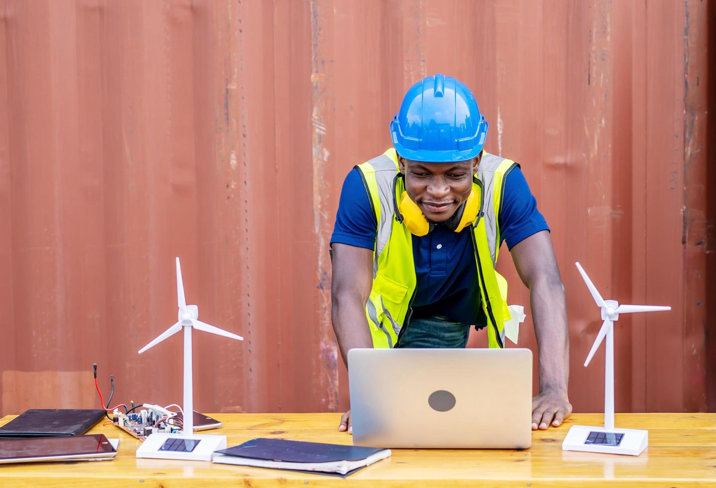 Ecology engineer typing on laptop and working on project. On desk are windmill models. Sustainable development concept photo