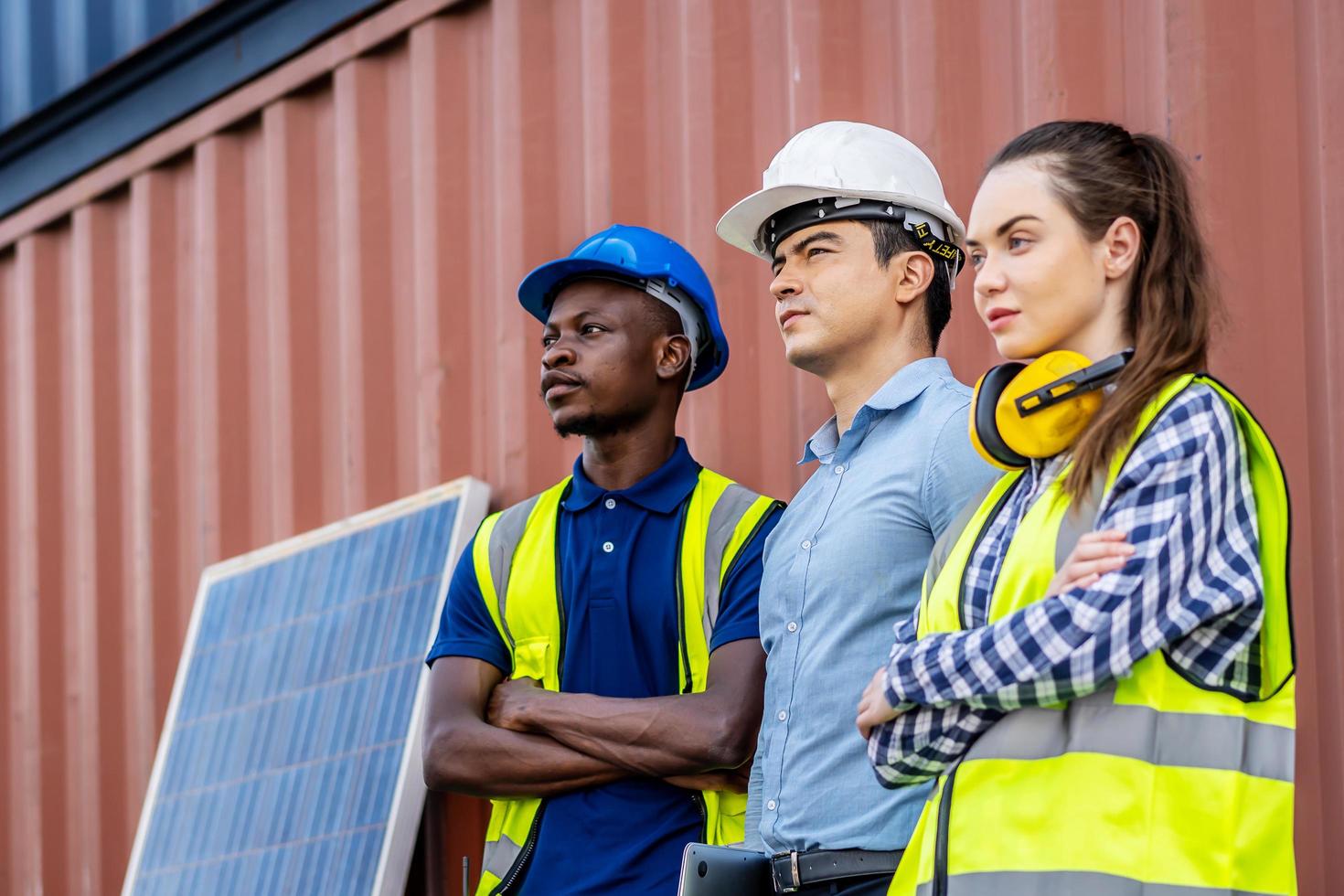 Confident foreman and engineers portrait in uniforms standing in front of the containers and solar cell, Sustainable development concept photo