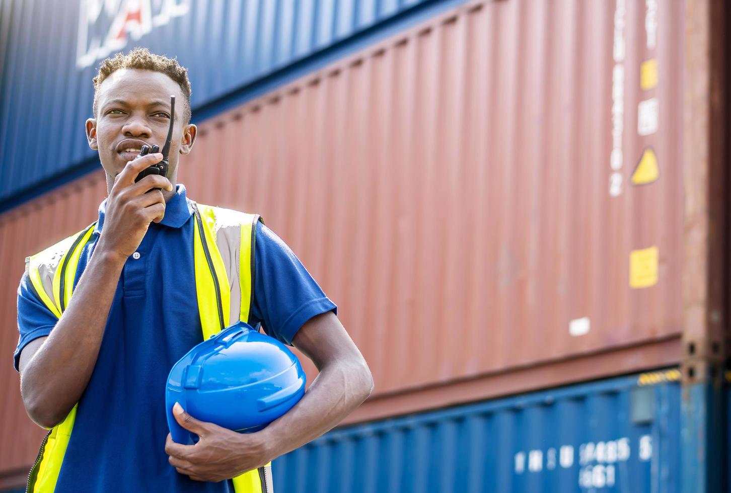 los trabajadores afroamericanos adultos verifican y controlan la carga de contenedores de carga mediante el uso de radio en el muelle de envío comercial sintiéndose curiosos. buque de carga para el concepto de exportación de importación foto