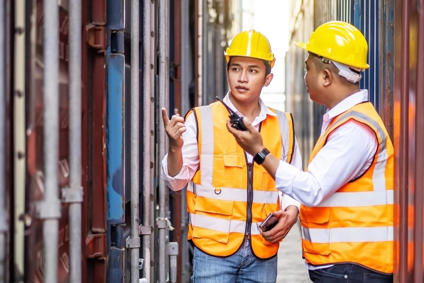 profesional de dos ingenieros o supervisores que revisan y controlan la caja de contenedores de carga de la carga en el puerto. concepto de transporte y logística foto