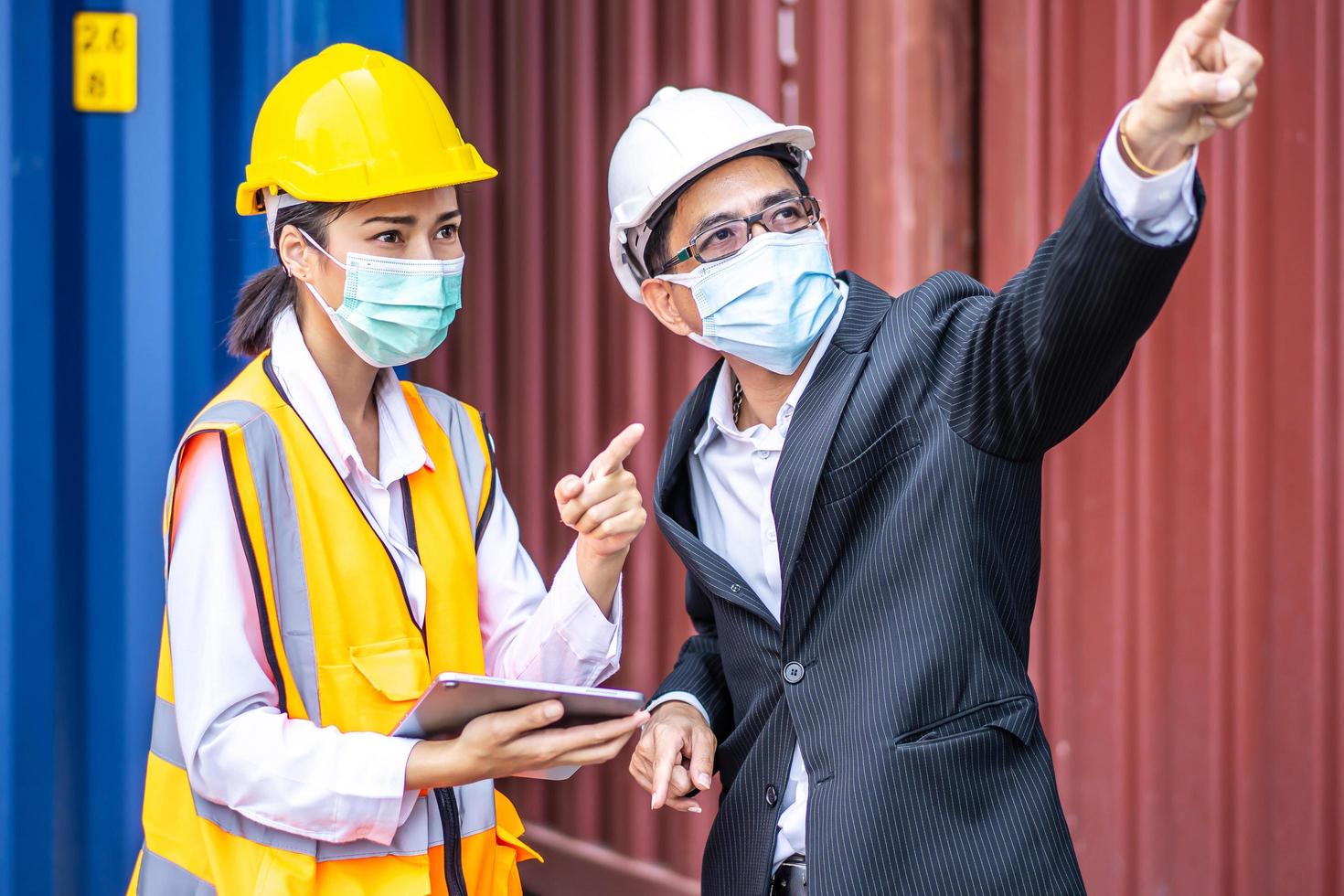 Industrial worker woman and engineer control worker using tablet device and meeting in front of container and cargo. Business people with confident and smart working in shipping transport industry photo