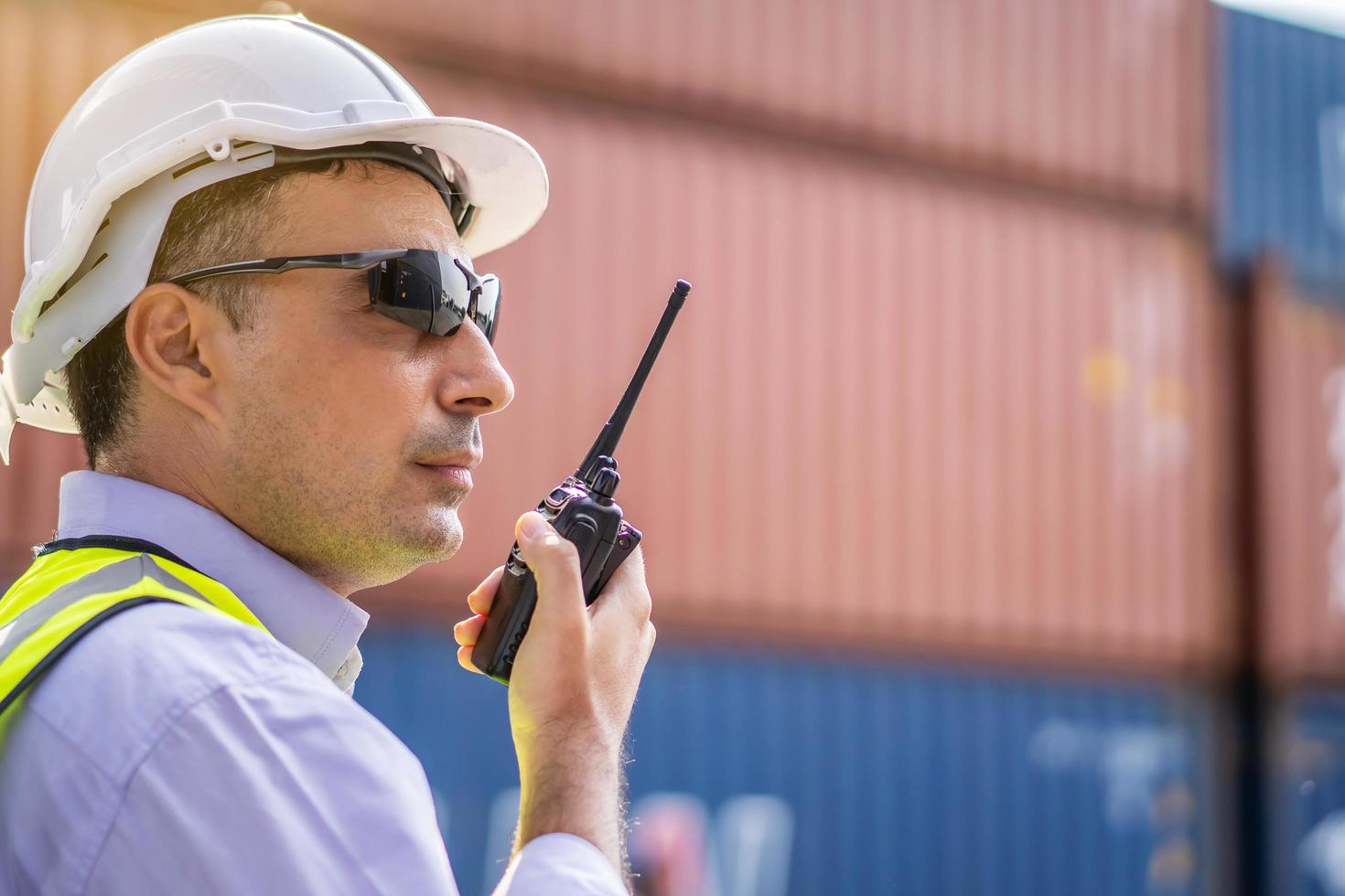 Young male engineer or manager Use of radio communication to control container load in industrial transport and logistics concepts. photo