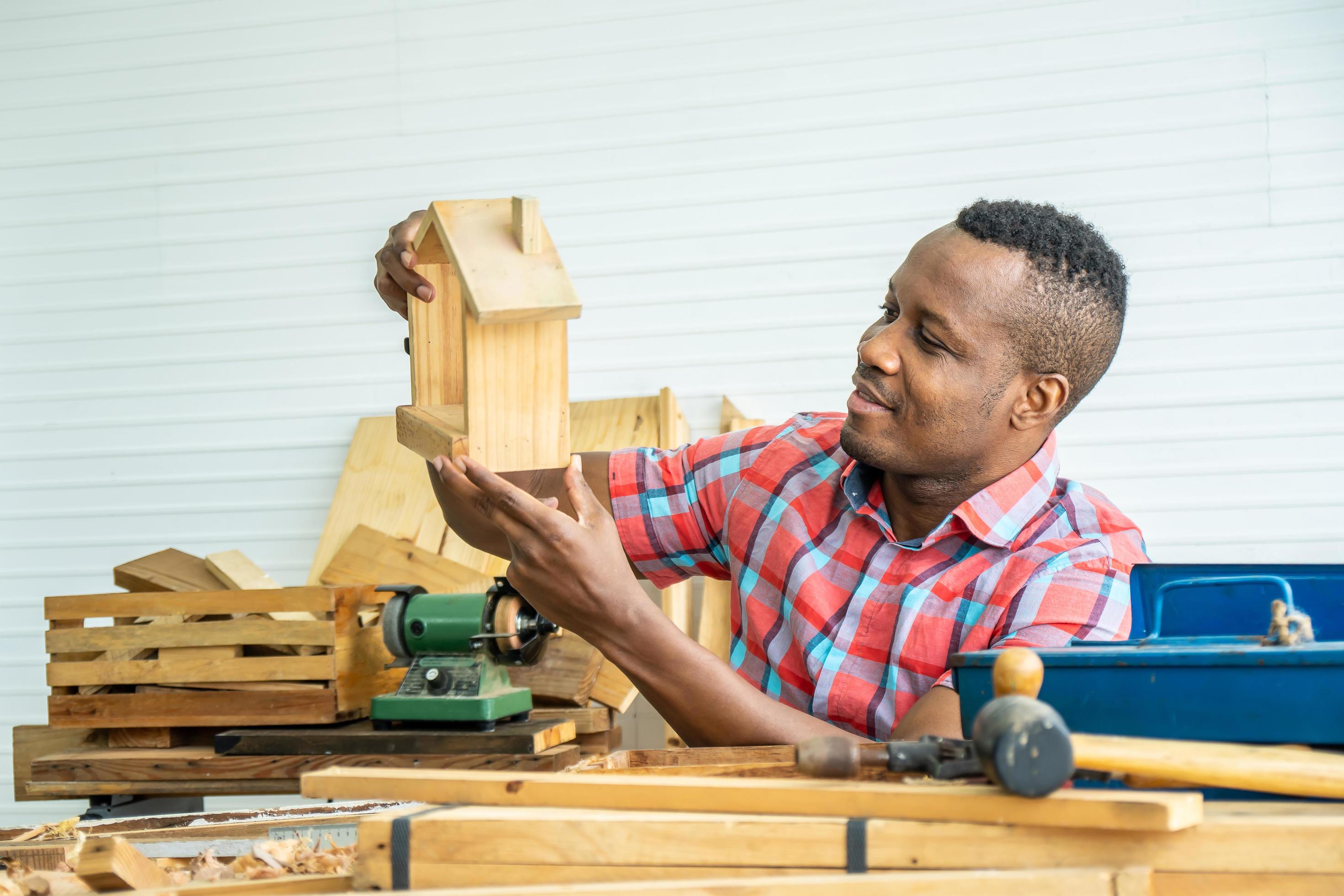 Young carpenter african american man look proudly at a model wooden Young carpenter african american man look proudly at a model wooden