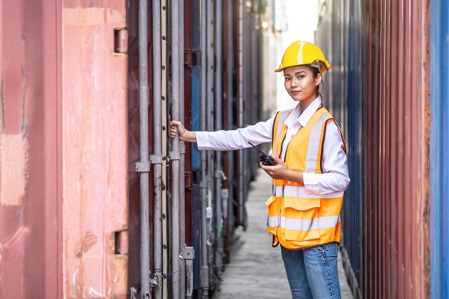 joven ingeniera segura de sí misma que usa comunicación por radio y usa casco de seguridad amarillo y verifica la caja de contenedores de carga de control del buque de carga para importación y exportación foto