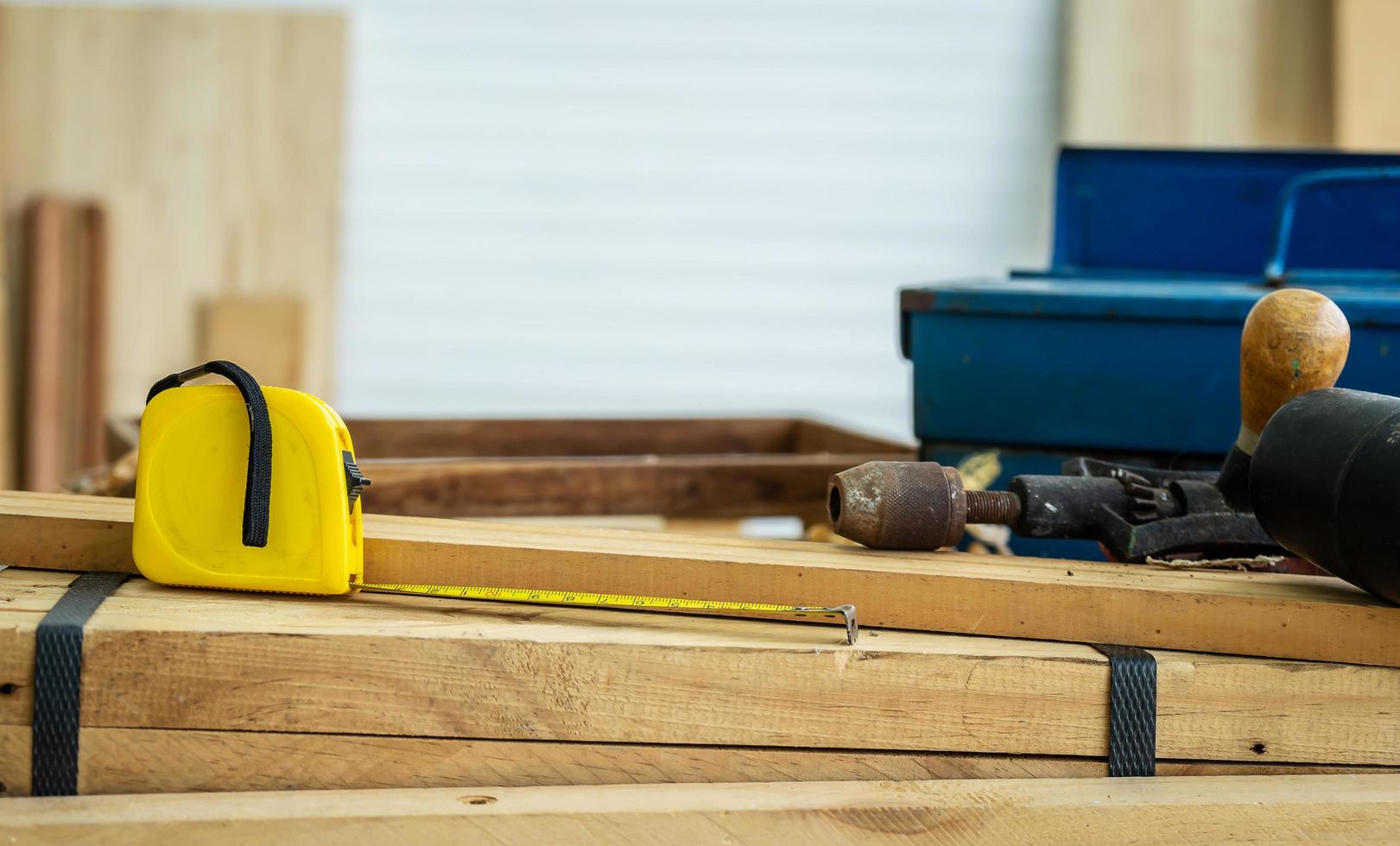 imagen de fondo de la estación de trabajo de carpinteros, mesa de trabajo de carpinteros con diferentes herramientas, cinta métrica desplegada en una tabla de madera, corte de madera con virutas de madera foto