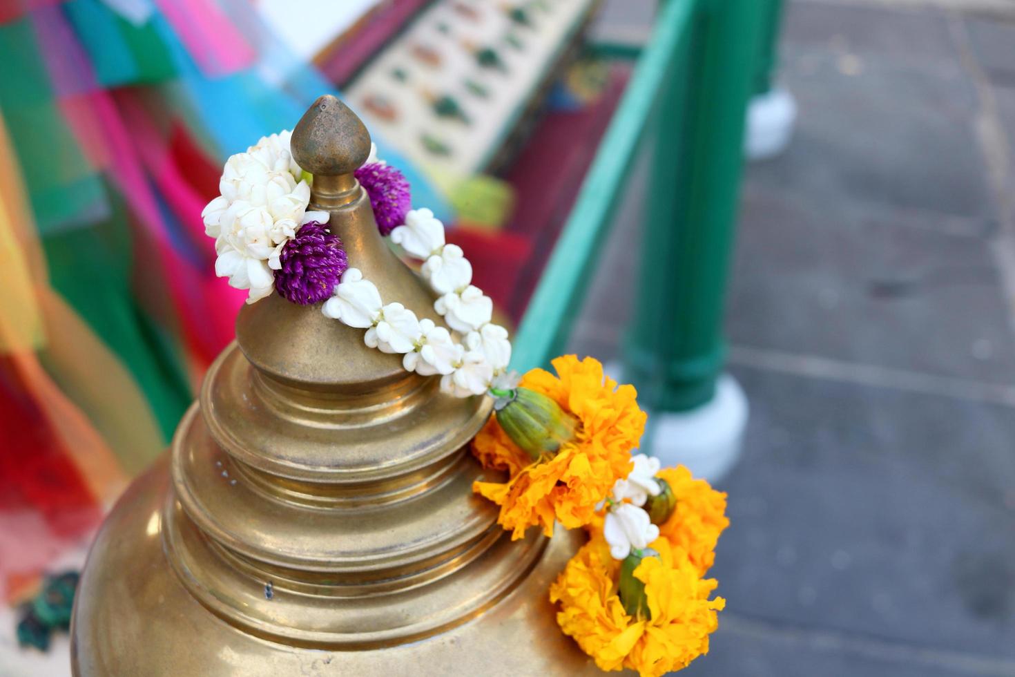 Brass top of small pillar in round shape Thai ancient style and flower garland hang on, native Thai style in temple of Thailand. photo