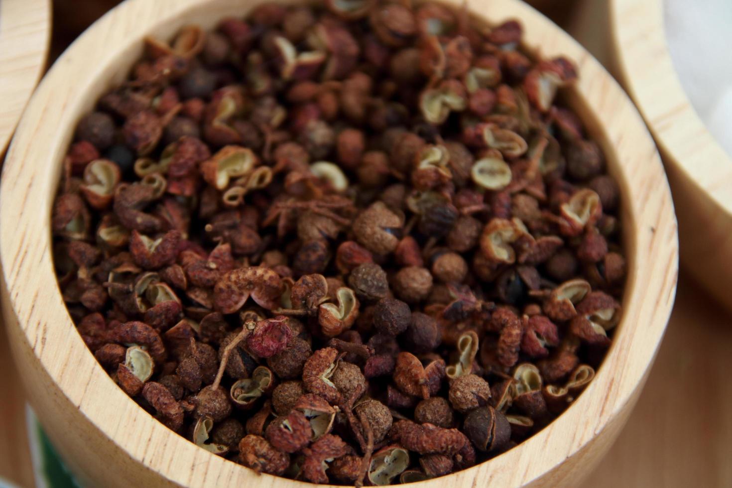 Fruits of Japanese prickly ash or Sichuan pepper in ligth brown bowl. Seed is black color and peel are cracked. photo