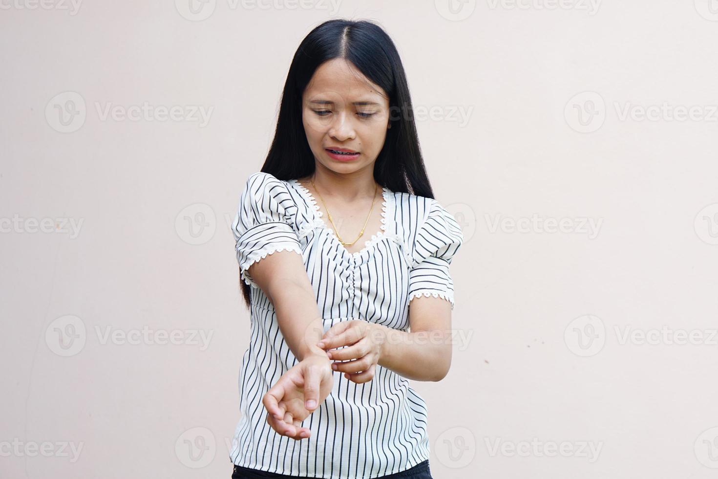 Woman scratching arm from itching on light gray background. Cause of itchy skin include insect bitesConcept of health care skin. photo