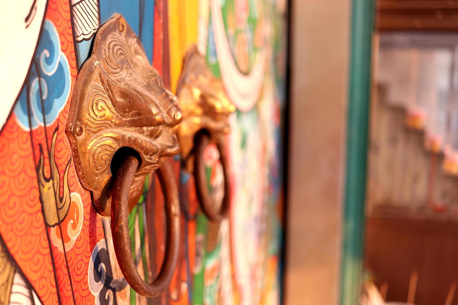 Brass door knobs are on bright colorful door and shape tiger head, the door knobs are design chinese style in shrine, Thailand. photo