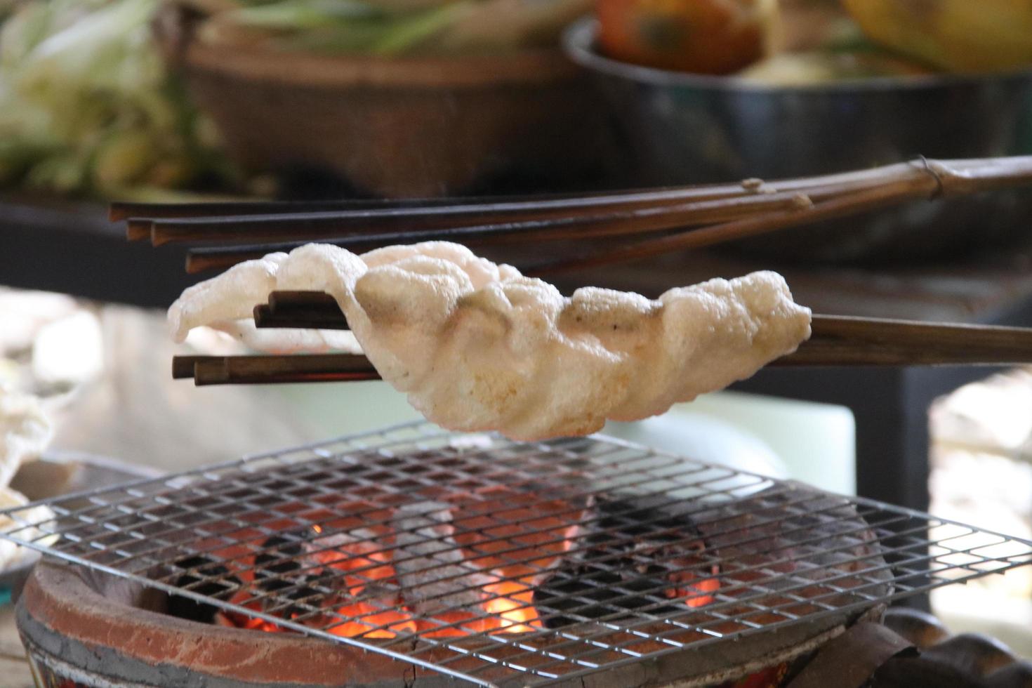 una galleta de arroz indígena se está asando sobre el fuego de una estufa de arcilla nativa, tailandia. foto