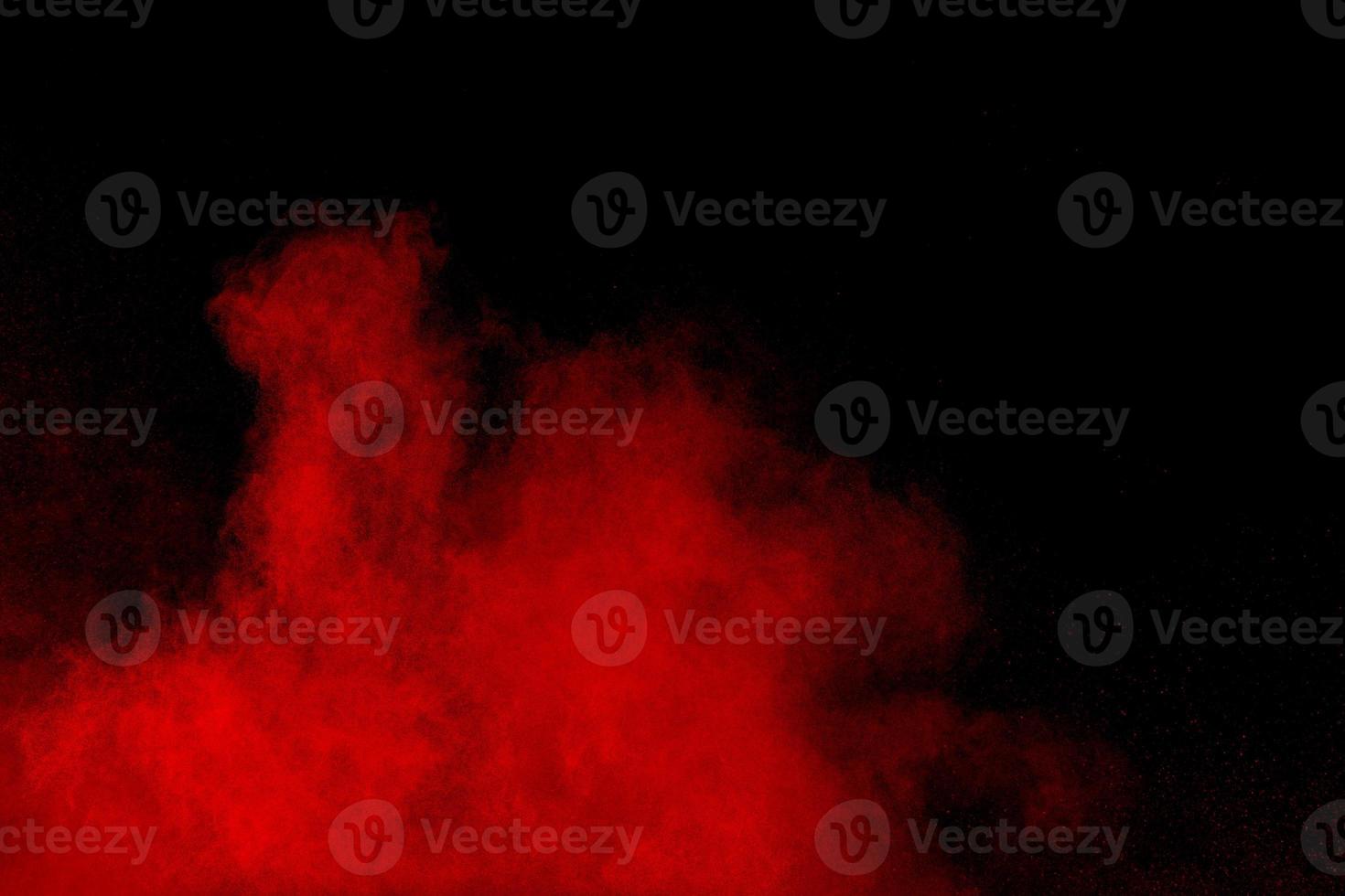 abstract red dust splattered on black background. Red powder explosion.Freeze motion of red particles splashing. photo