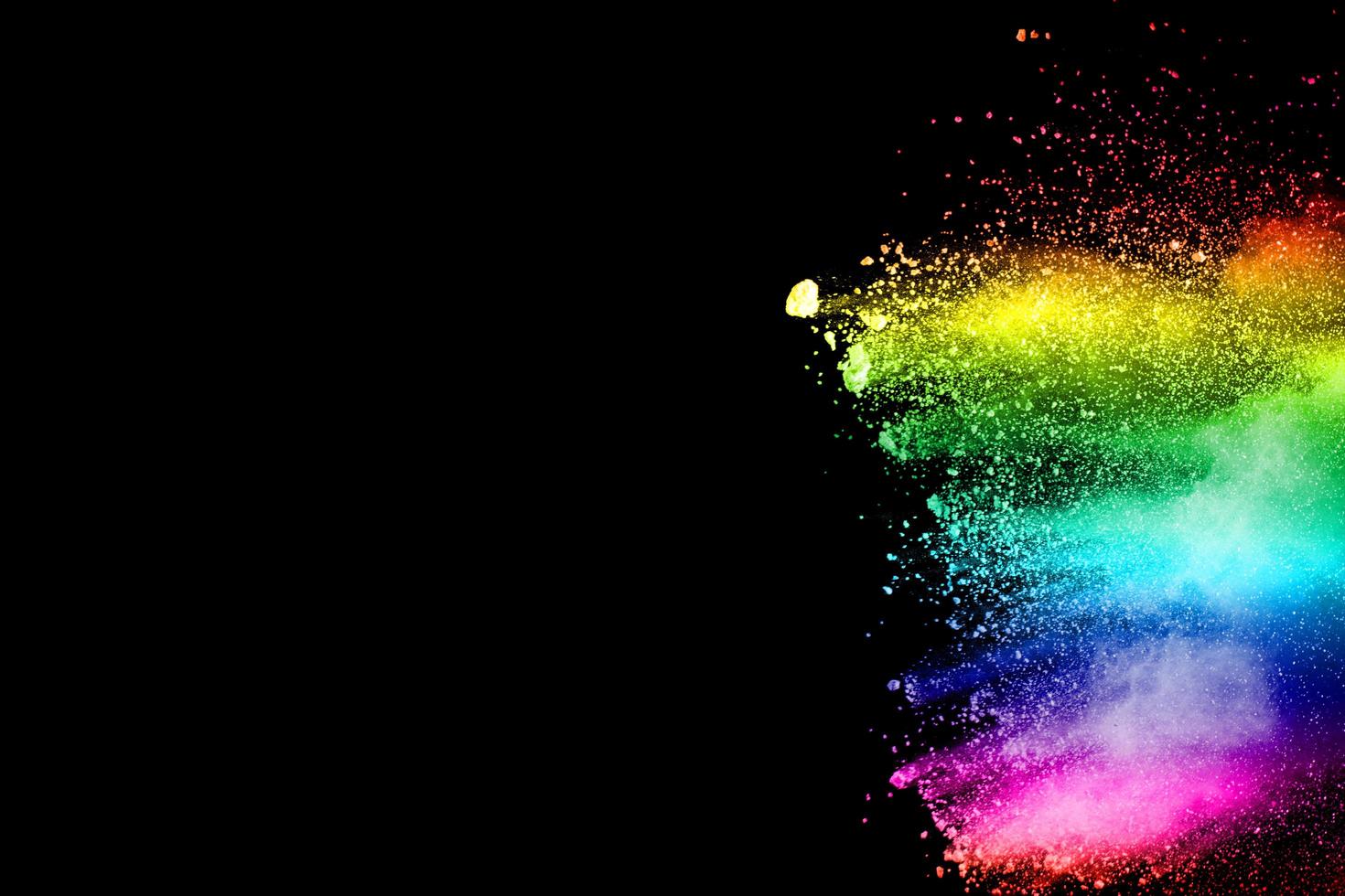 Abstract multicolored powder explosion on black background. Color dust particle splattered on background. photo