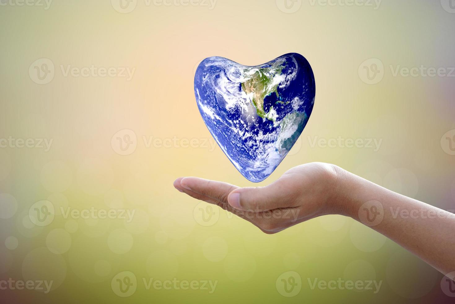 Earth conservation concept. The world of hearts floats above human hands. nature blur background photo