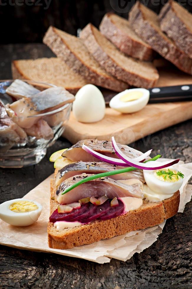 Sandwich of rye bread with herring, beets, onions and egg photo
