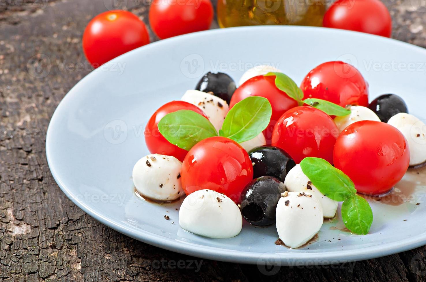 ensalada fresca con tomates cherry, albahaca, mozzarella y aceitunas negras. foto