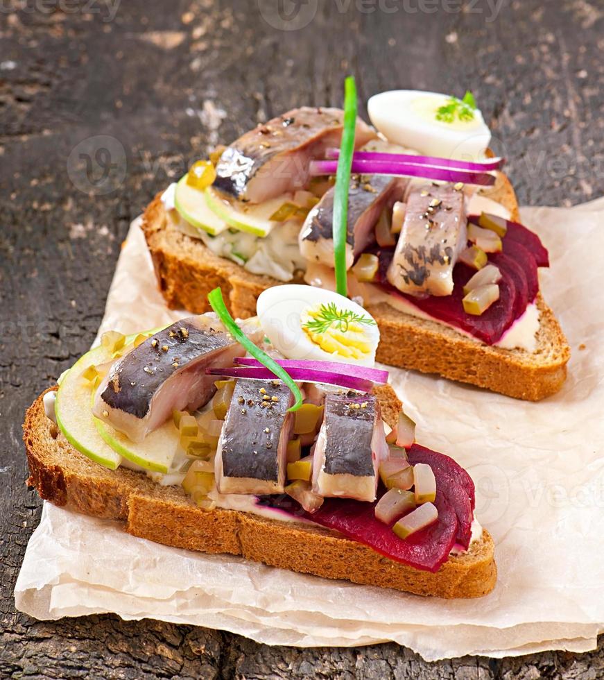 Sandwich of rye bread with herring, beets, onions and egg photo