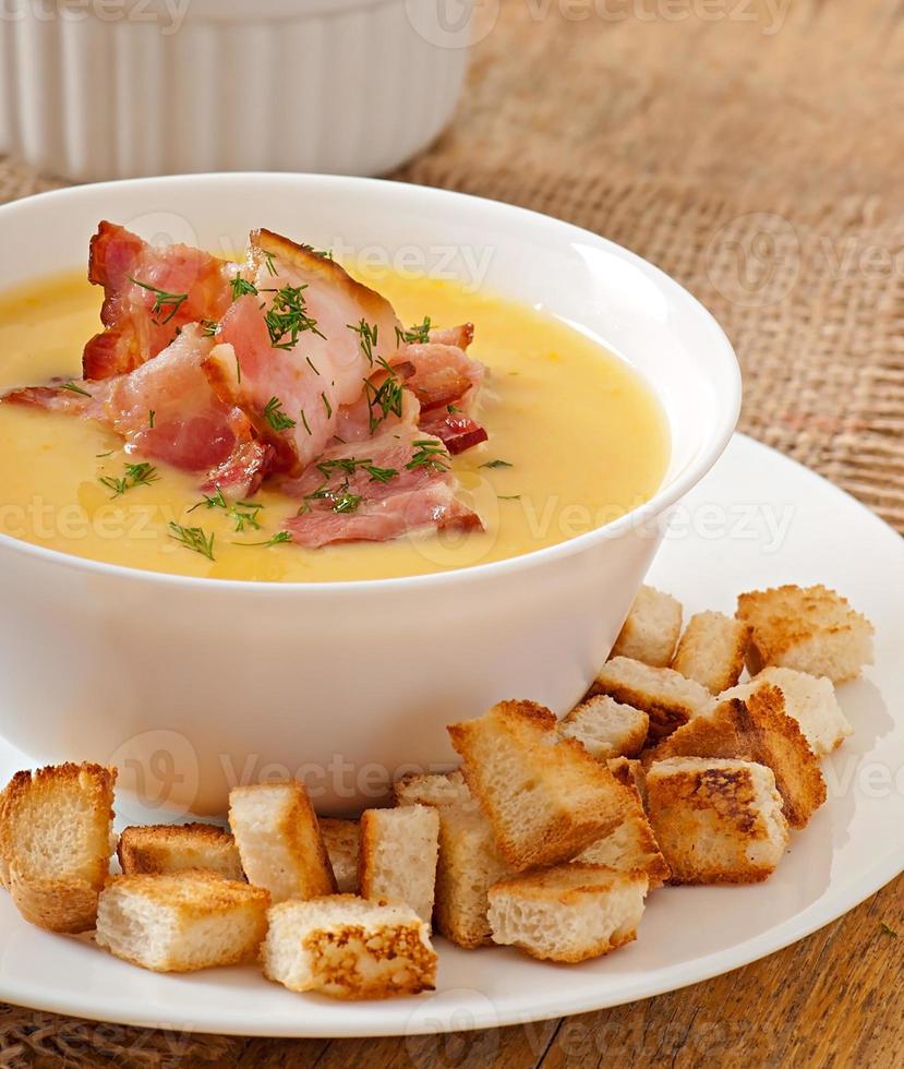 Cream soup of peas with fried bacon and croutons photo