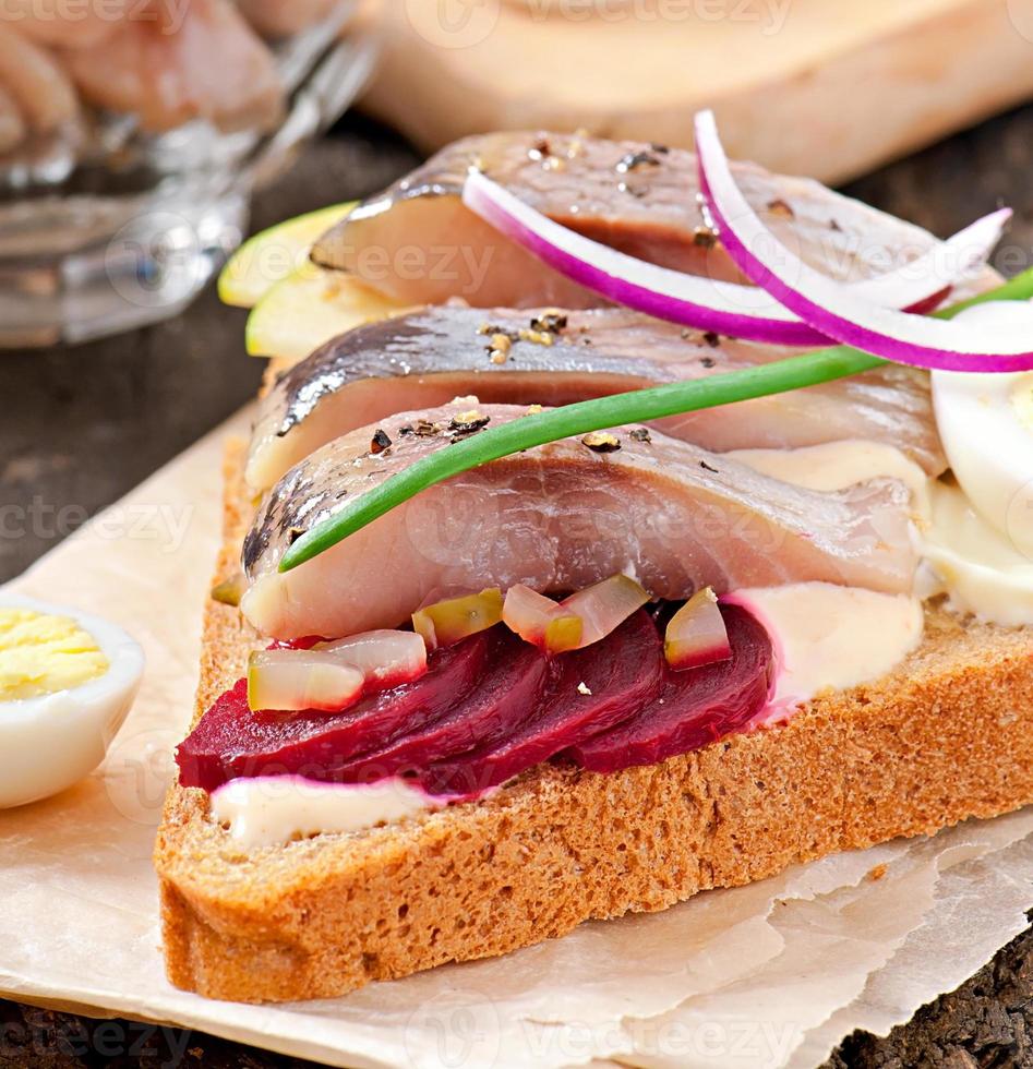 Sándwich de pan de centeno con arenque, remolacha, cebolla y huevo foto