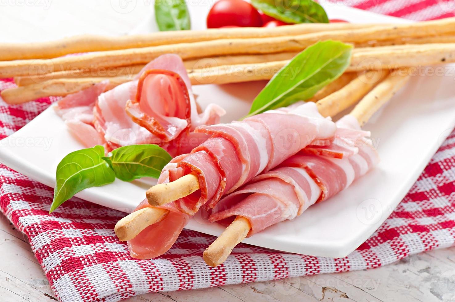 Grissini bread sticks with ham, tomato and basil photo