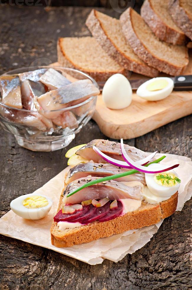 Sándwich de pan de centeno con arenque, remolacha, cebolla y huevo foto