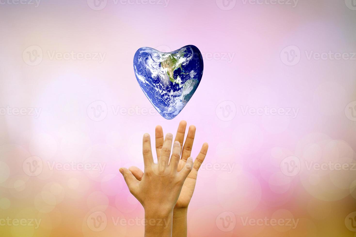 concepto de conservación de la tierra. el mundo de los corazones flota sobre las manos humanas. fondo borroso de la naturaleza foto