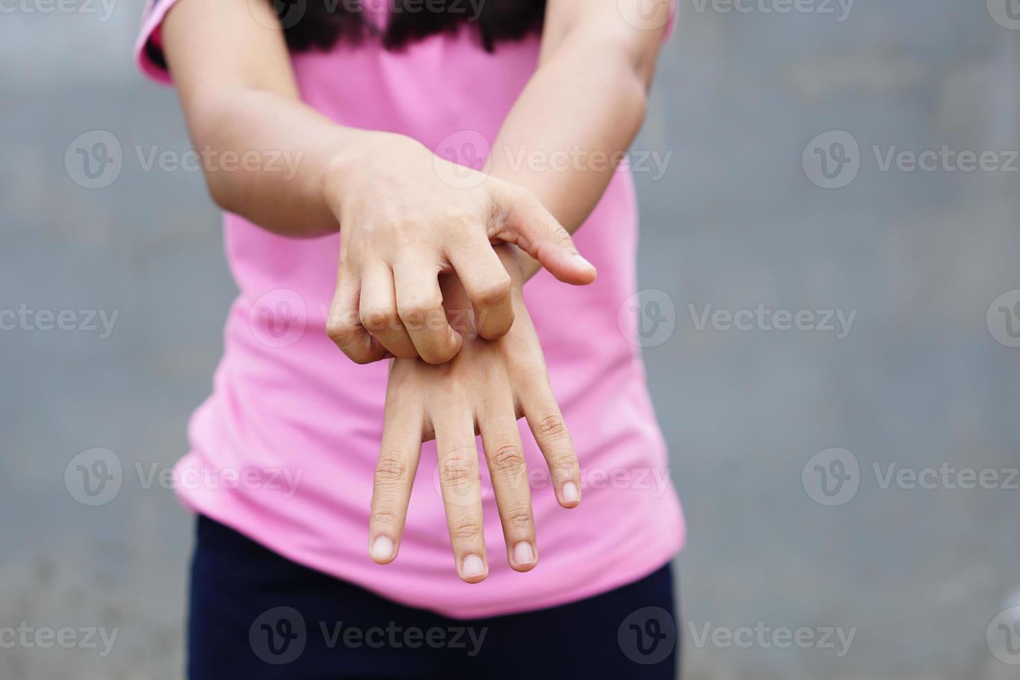 mujer rascándose el brazo por picazón en un fondo gris claro. la causa de la picazón en la piel incluye picaduras de insectos concepto de cuidado de la salud de la piel. foto