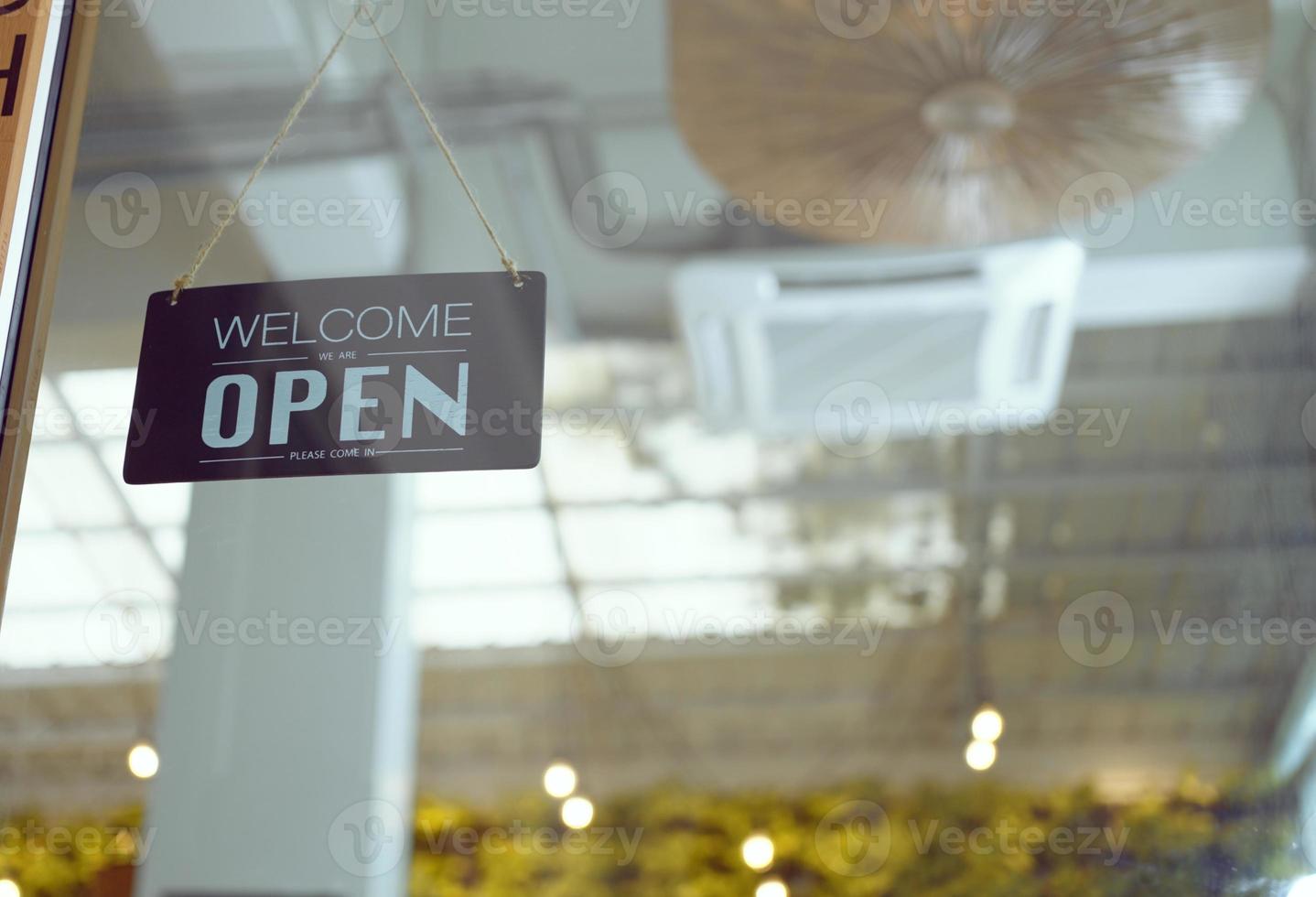 Welcome we're open in a coffee shop or restaurant hung at the entrance door. photo