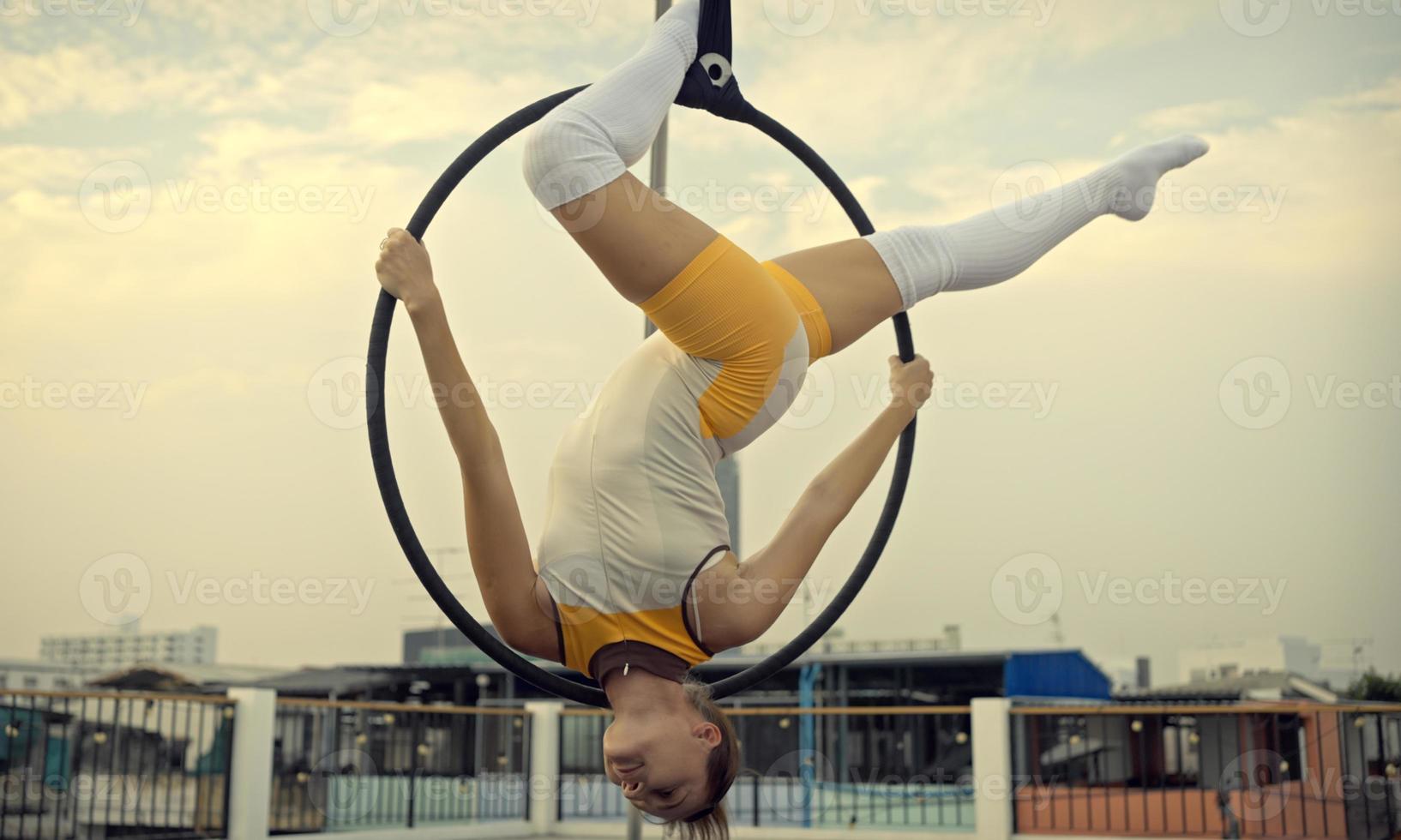 Woman in sportswear doing sky yoga on the rooftop in the evening when the sun set. Self care and health concepts. photo