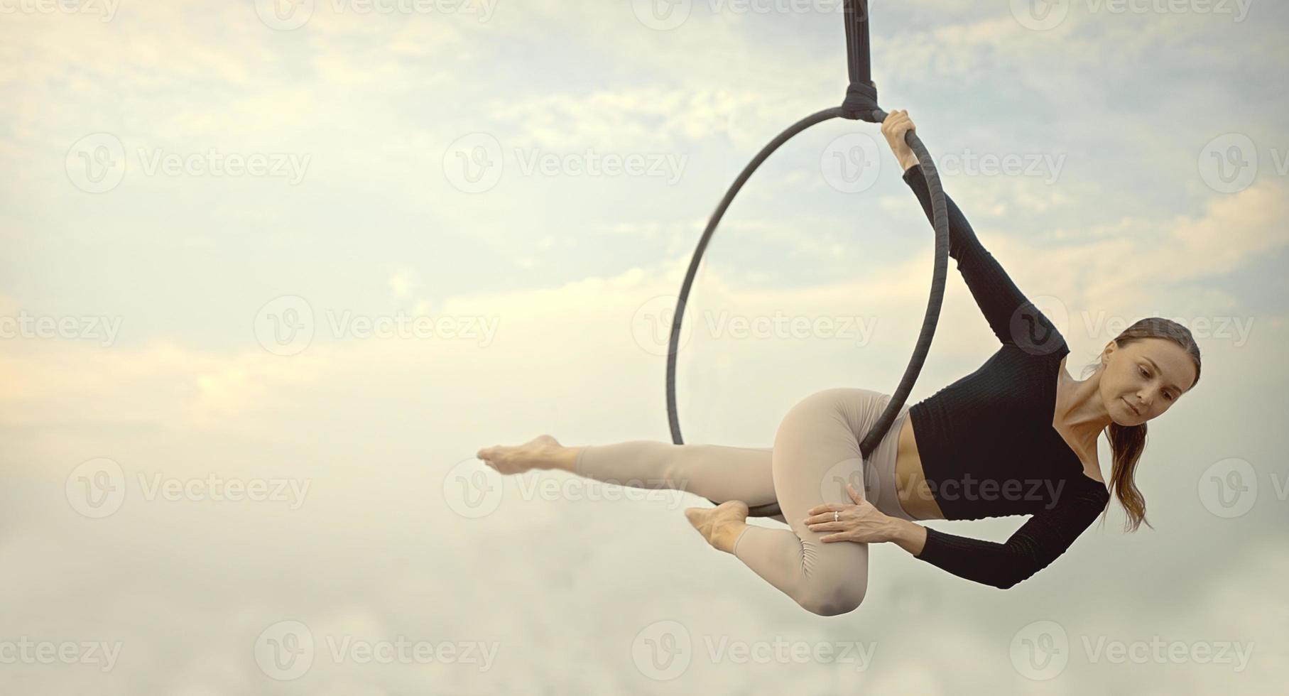 Woman in sportswear doing sky yoga on the rooftop in the evening when the sun set. Self care and health concepts. photo