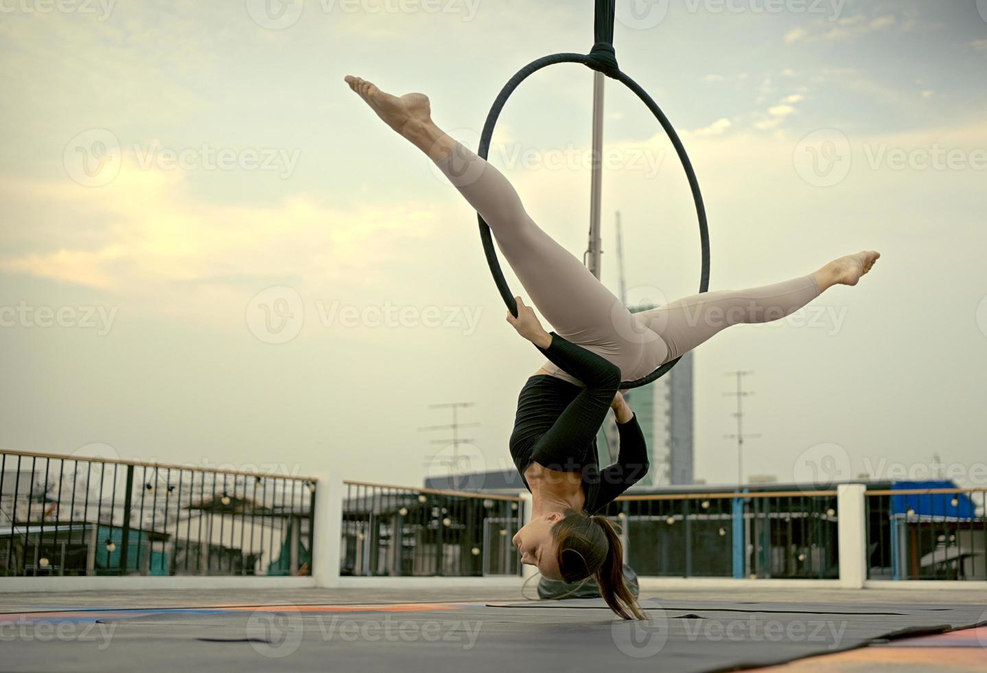 Woman in sportswear doing sky yoga on the rooftop in the evening when the sun set. Self care and health concepts. photo