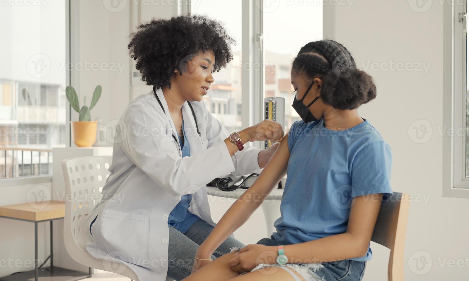 médico afroamericano está aplicando yeso en el hombro de un niño después de ser vacunado. abrir mangas para vacunar contra la gripe o la epidemia en la atención de la salud y el concepto de vacunación. foto