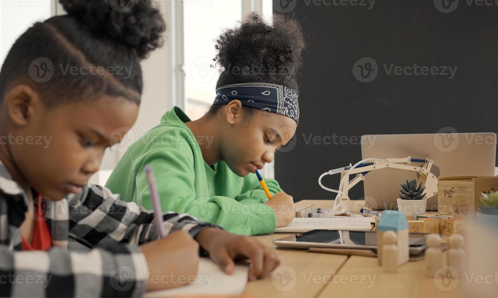 estudiante en preescolar internacional escribiendo un libro juntos en la clase de la escuela primaria, los alumnos disfrutan estudiando en el aula. foto