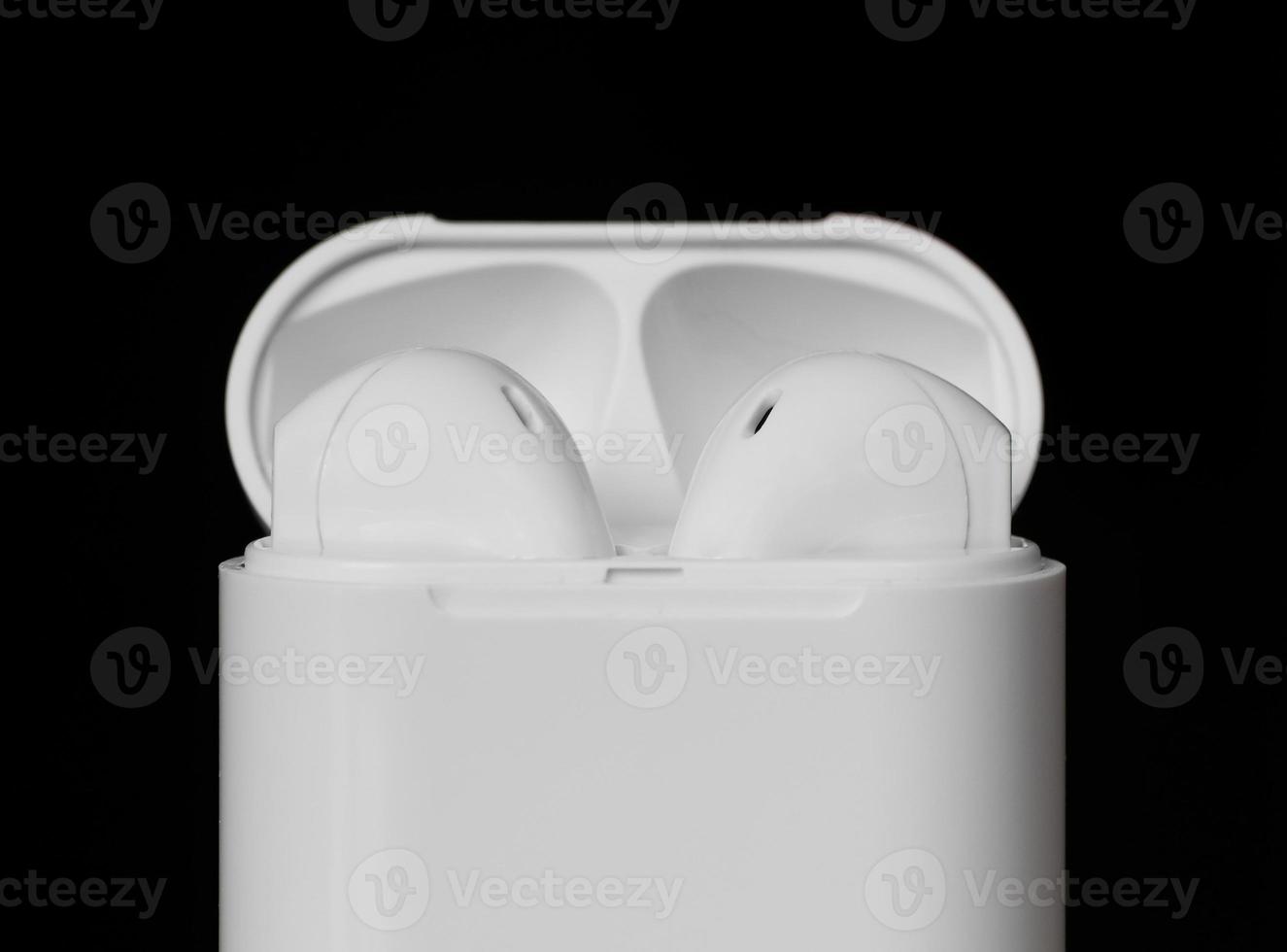 Close up white color true wireless earphone in charging case isolated on black background. Selective focus. photo