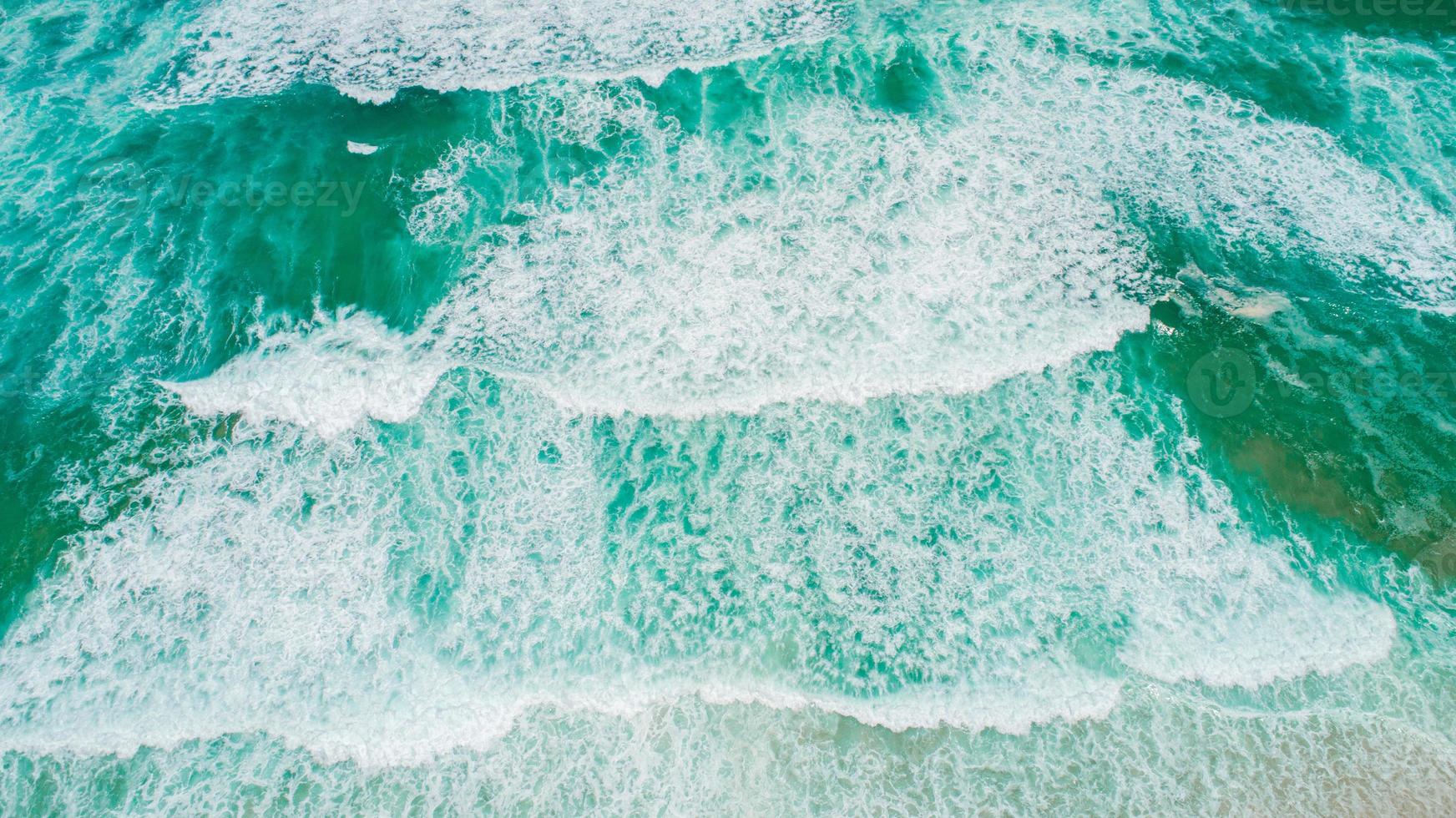 ondas de textura de vista superior, espuma y salpicaduras en el océano, día soleado foto