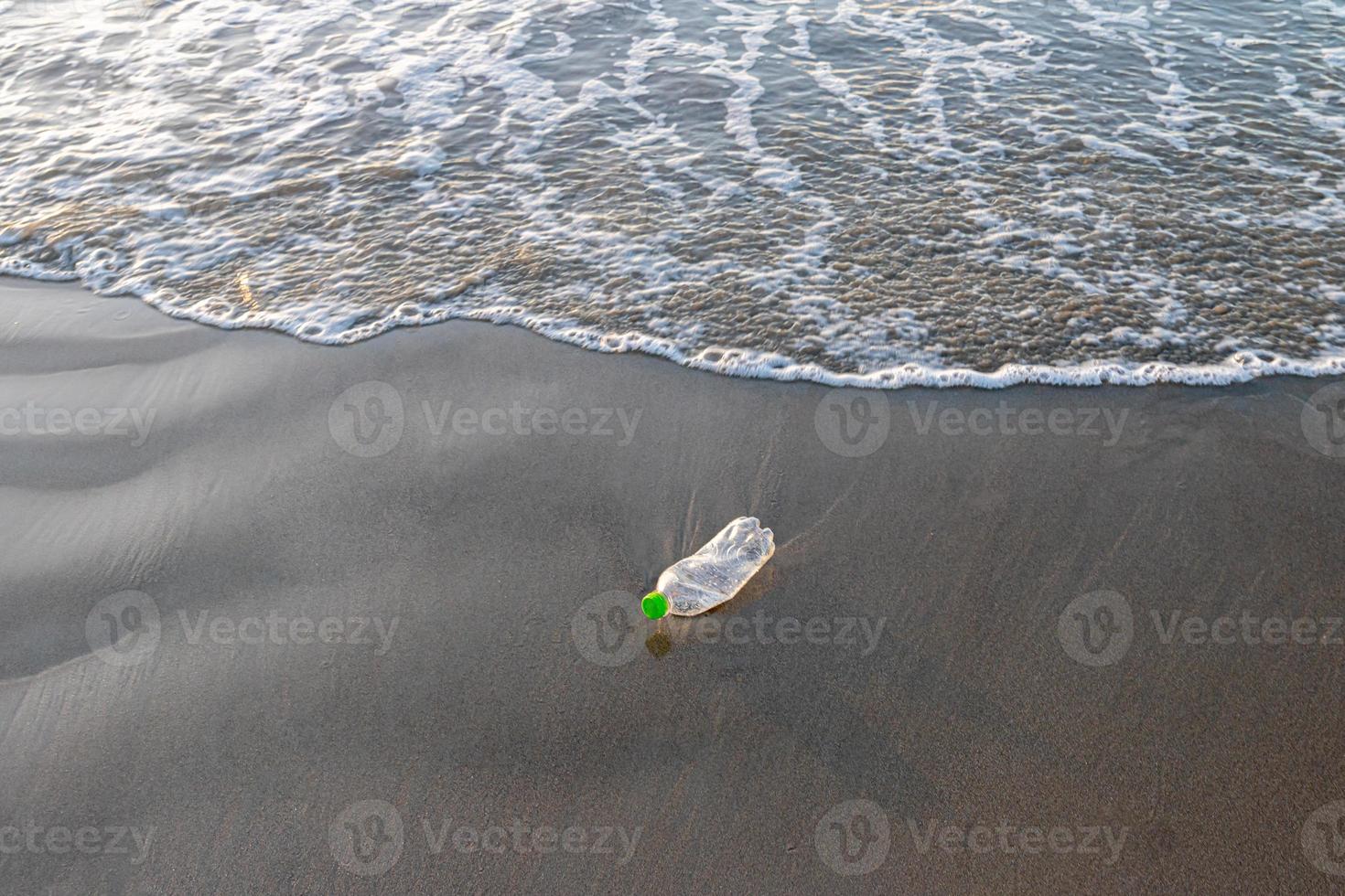 Reduce the use of plastic bottles, recycling the empty used plastic bottle. A discarded plastic bottle is washed up on a sandy beach. Ecology, earth protection, nature conservation, pollution sea. photo