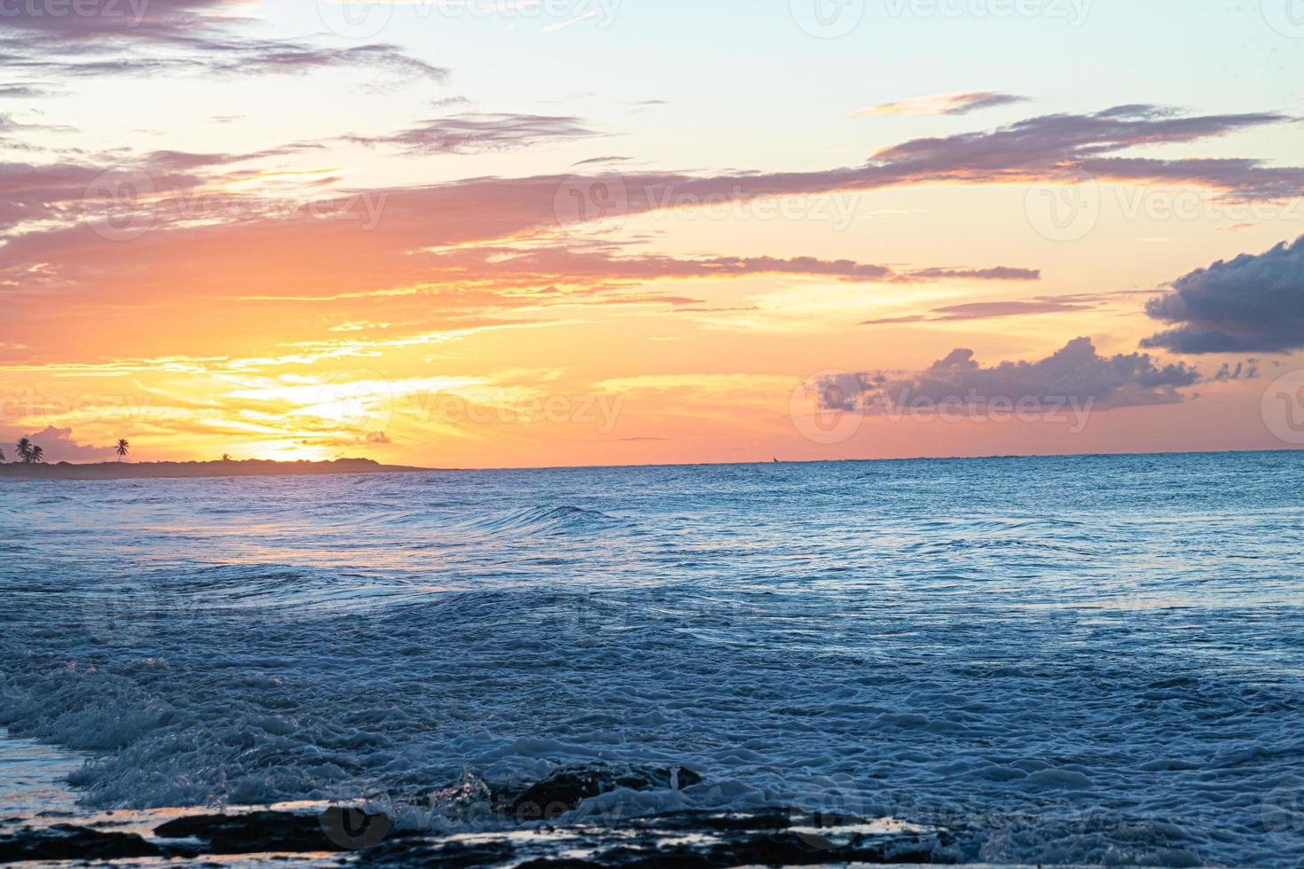 Scenic sunset over the sea. The sun sets on the water. Clouded sky is painted with bright colors. Sunset beach in a summer evening. Brazil. photo