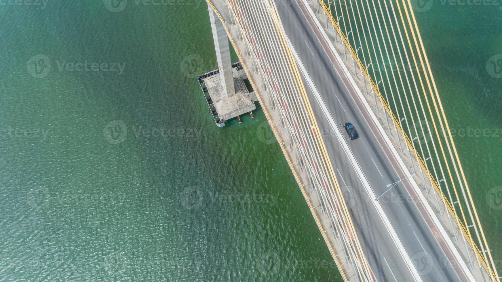 vista aérea de la conducción de automóviles en un puente con árboles de bosque natural, arena, playa tropical y olas rodando hacia la orilla. foto