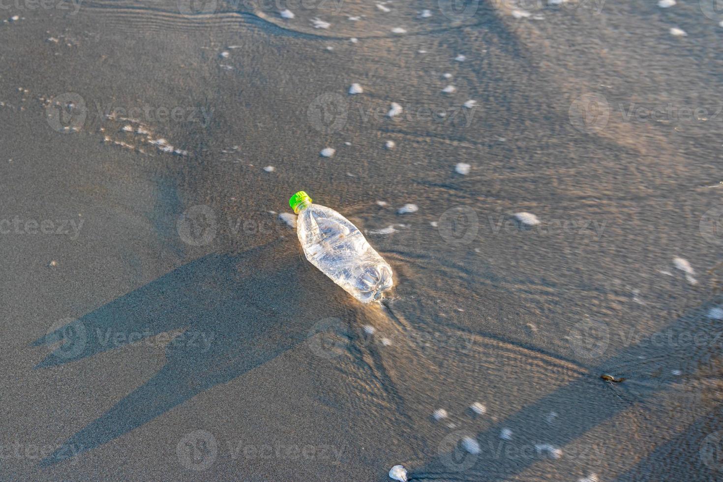 Reduce the use of plastic bottles, recycling the empty used plastic bottle. A discarded plastic bottle is washed up on a sandy beach. Ecology, earth protection, nature conservation, pollution sea. photo