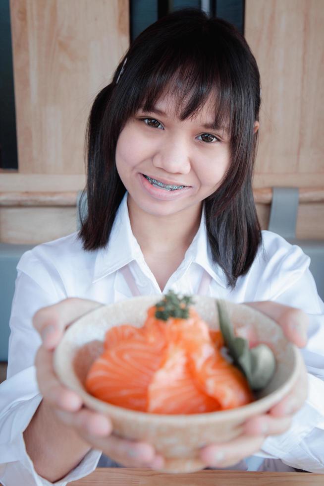 una adolescente muestra un don salmón en un restaurante japonés. foto