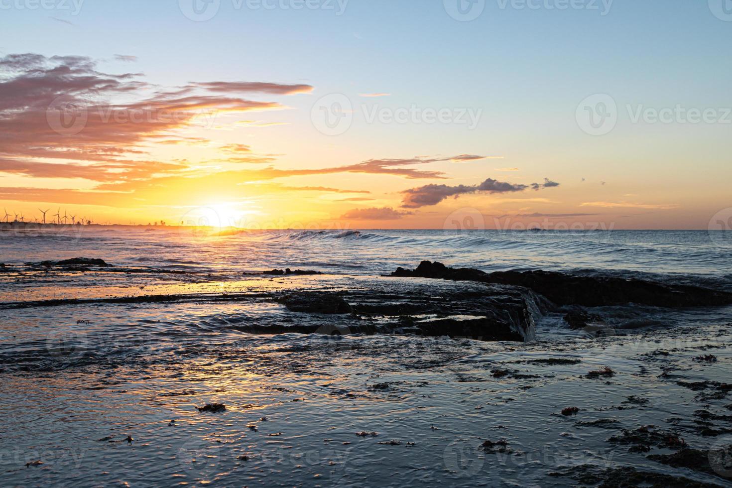 Scenic sunset over the sea. The sun sets on the water. Clouded sky is painted with bright colors. Sunset beach in a summer evening. Brazil. photo