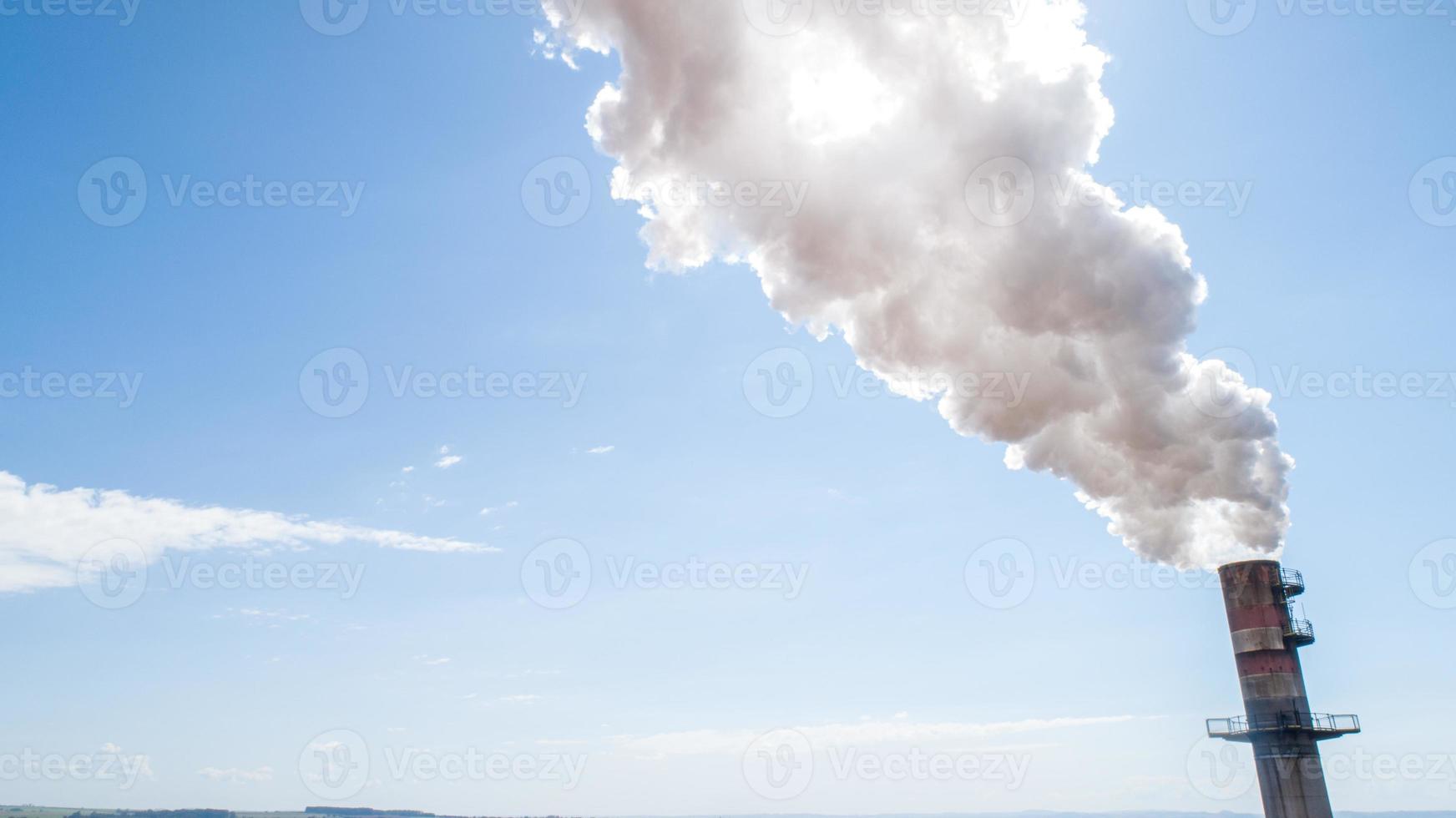 Air pollution from power plant chimney. Dirty smoke on the sky, ecology problems. photo
