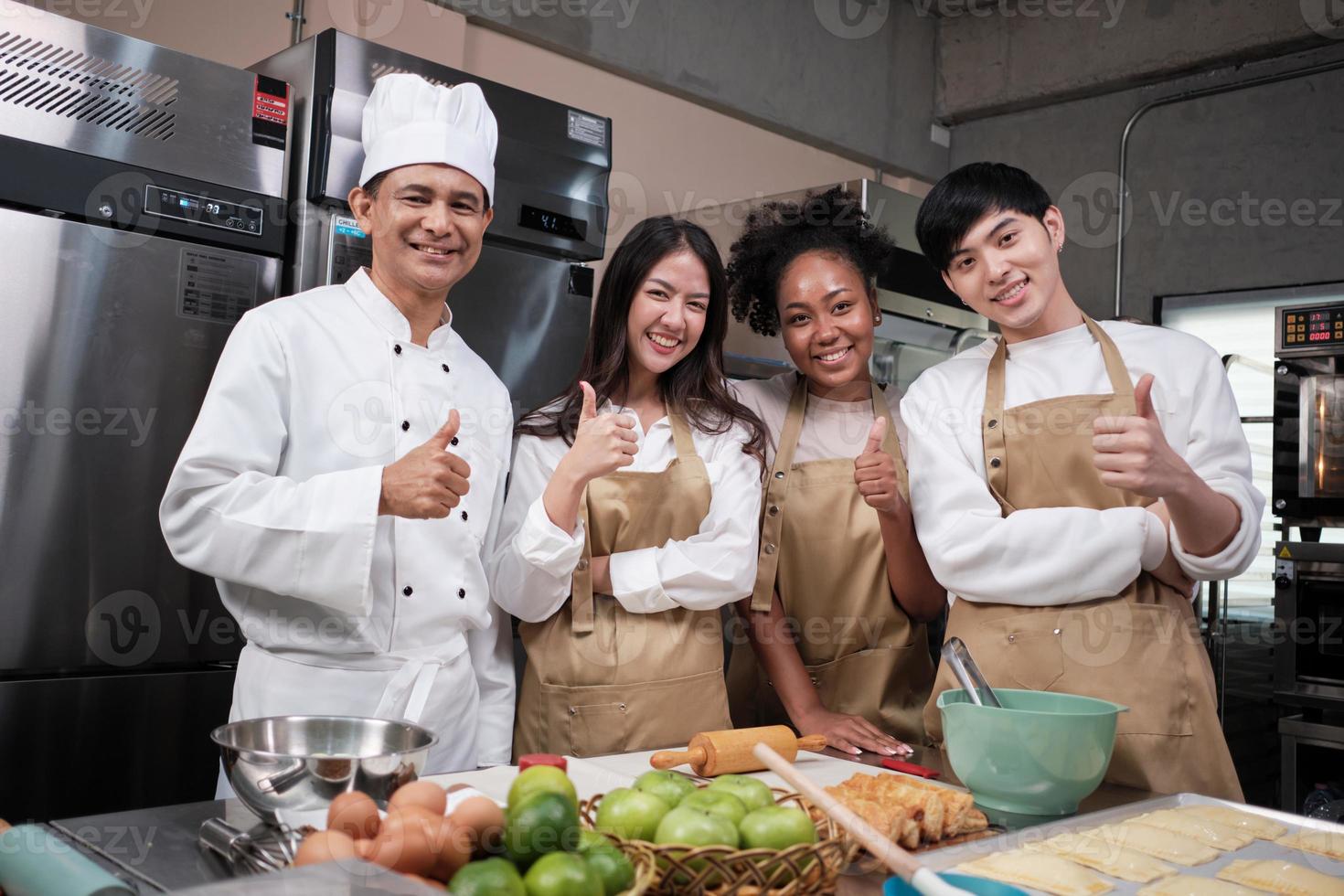 Portrait of professional cooking class people, senior male chef, and young students team looking at camera, cheerful smile and thumb up in kitchen, pastry foods and bakery course for small business. photo