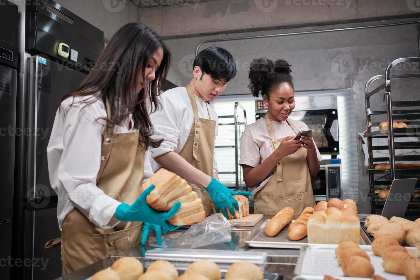 Three young friends and startup partners of bread dough and pastry foods busy with homemade baking jobs while cooking orders online, packing, and delivering on bakery shop, small business entrepreneur photo