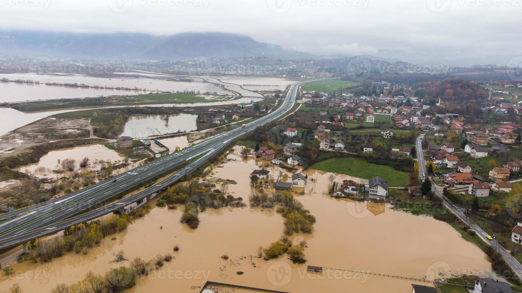 Aerial drone view of torrential rain causes flash floods in residential areas. Houses and roads surrounded by water. Climate change. Heavy rainfall consequences. photo